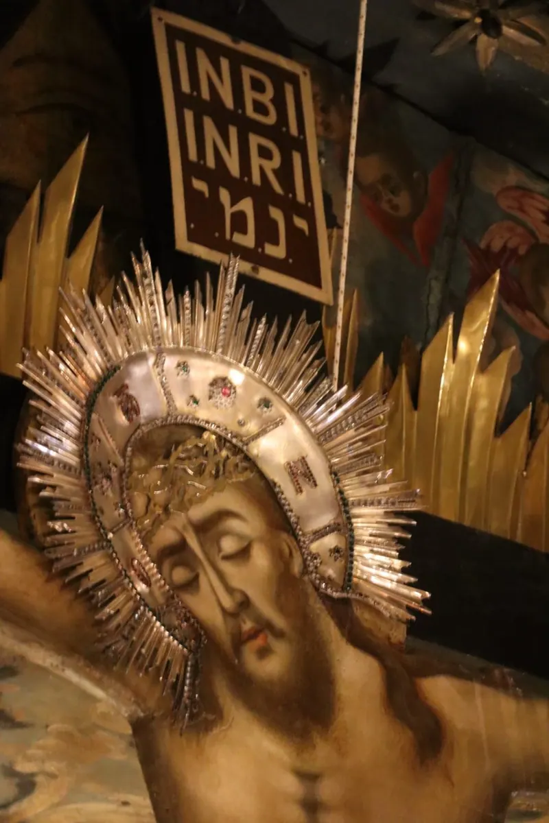 צלוב מצויר ועליו הילת כסף זוהרת, ומעליו לוח הכתובת INRI באותיות לטיניות ועבריות.