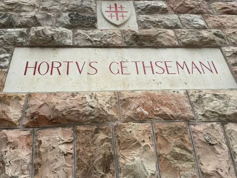 לוח אבן בקיר ועליו הכיתוב הלטיני HORTVS GETHSEMANI, ומעליו מגן עם צלב ירושלים.