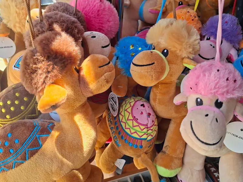 גמלי פרווה צבעוניים תלויים בחנות מזכרות, עם תגיות מזכרת מירושלים.