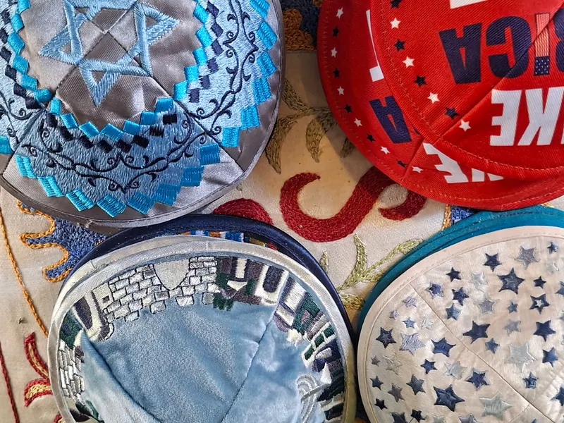 כיפות רקומות למכירה: אחת עם מגן דוד, אחת עם חומות ירושלים ואחרות בכוכבים ובאותיות.