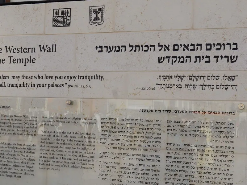 שלט אבן: "ברוכים הבאים אל הכותל המערבי, שריד בית המקדש", עם פסוק מתהלים וטקסט הסבר.