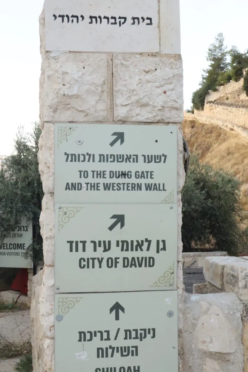 עמוד שילוט מאבן: חצים אל שער האשפות והכותל, אל גן לאומי עיר דוד ואל ניקבת ובריכת השילוח.