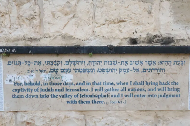 לוח על קיר אבן ובו פסוק מספר יואל בעברית ובאנגלית, על קיבוץ הגויים בעמק יהושפט.