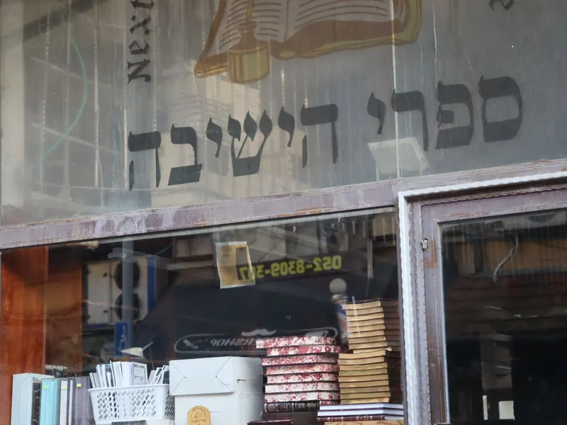 חלון ראווה של חנות ועליו הכיתוב "ספרי הישיבה", וערימות ספרים מאחורי הזכוכית.