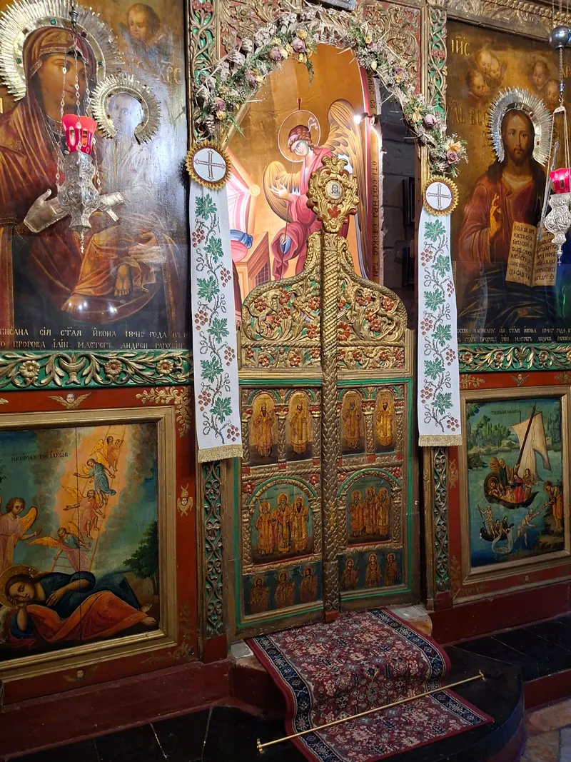איקונוסטזיס מעץ מגולף ומוזהב, ובו איקונות של מרים, ישו וקדושים ושער מרכזי מצויר.