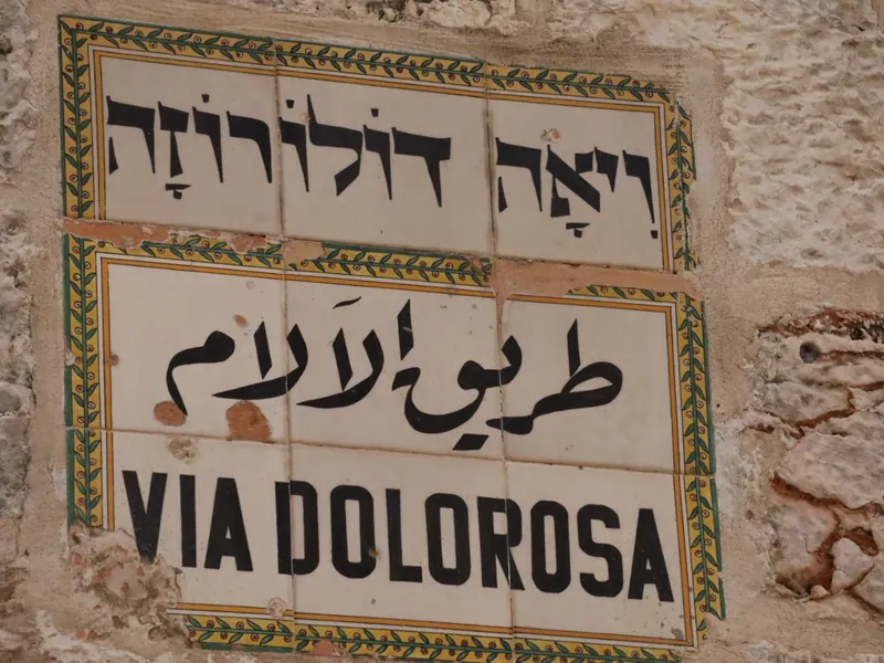 שלט אריחי קרמיקה על קיר אבן: ויה דולורוזה בעברית, בערבית ובאנגלית.