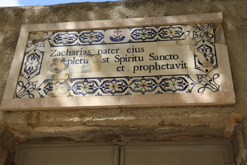 לוח אריחים סדוק מעל דלת, ועליו בלטינית "Zacharias pater eius repletus est Spiritu Sancto et prophetavit", ומעליו צלב ירושלים.
