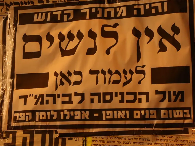 מודעת קיר מודפסת: "והיה מחניך קדוש – אין לנשים לעמוד כאן מול הכניסה לביהמ"ד, בשום פנים ואופן".