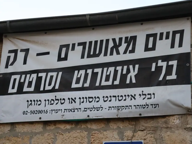 שלט בד גדול על קיר אבן: "חיים מאושרים – רק בלי אינטרנט וסרטים".