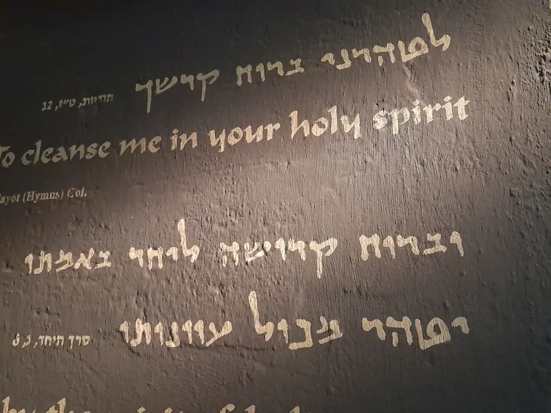 כתובת על קיר כהה בכתב מגילות עברי ובאנגלית: "To cleanse me in your holy spirit".